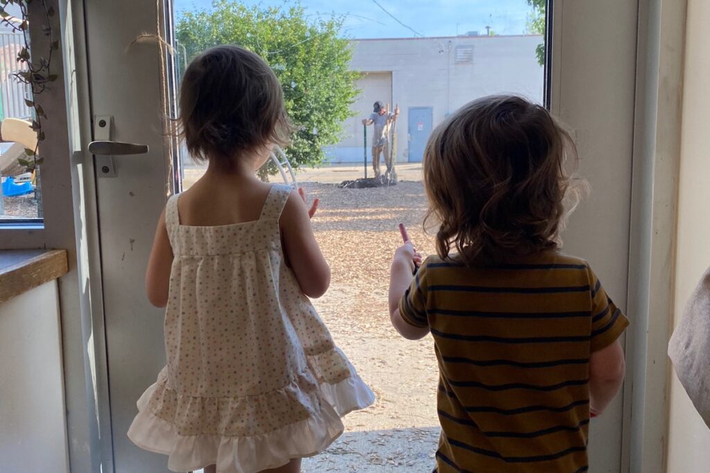 Children watch the crew install a new fence.