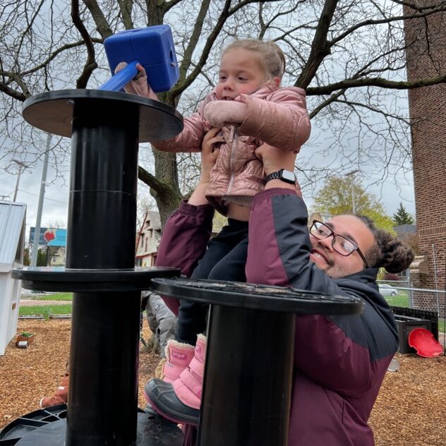Teacher helps Discovery student reach the top of the playground tower.