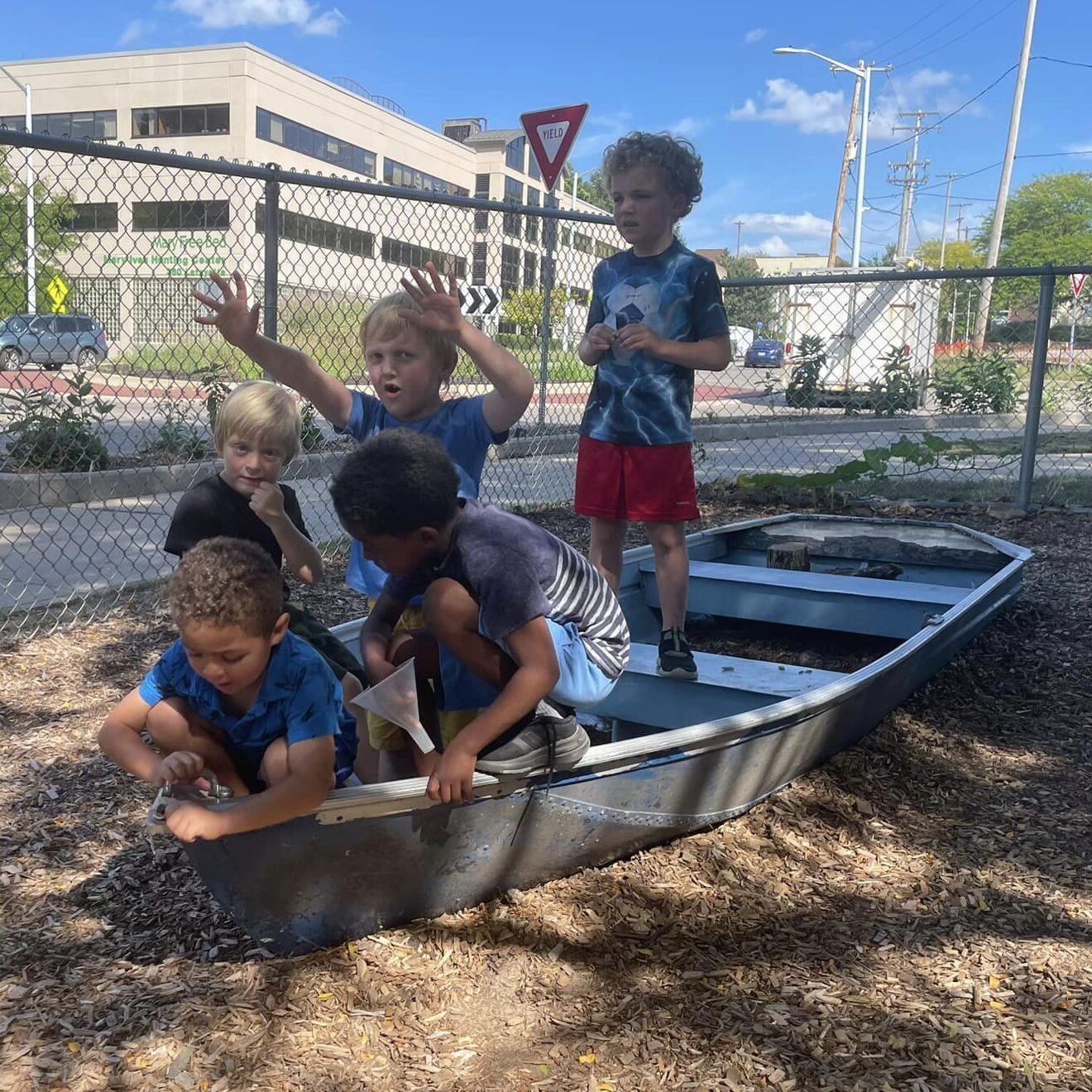 Kindergarten students make believe in the playground boat.