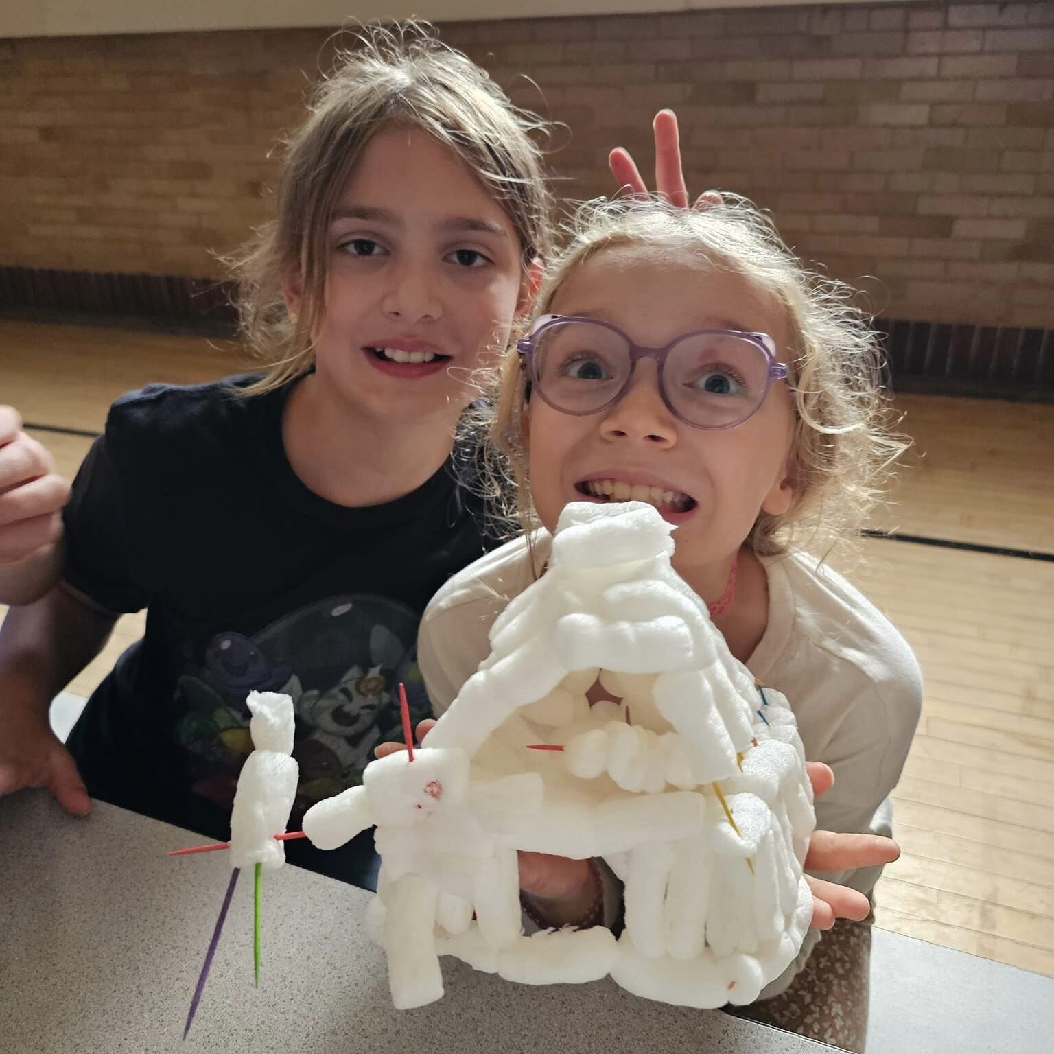 Violet and Stella pose next to their craft house