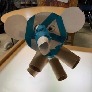 An elephant made from a whole paper plate, using empty paper towel rolls for legs and trunk.