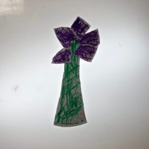 A purple flower made from cutouts of a paper plate.