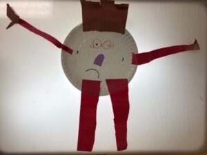 A sad person made from a plate with paper arms, legs, and hair.