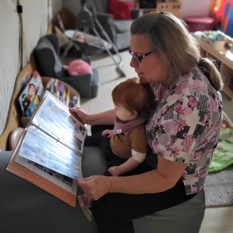 Penny and an infant looks at pictures of his family.