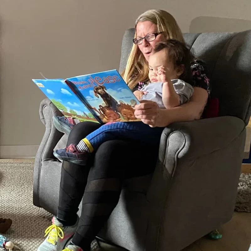 Penny reading a book to an infant.