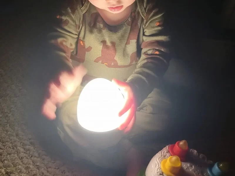 Infant holds his hands up to a strong egg light.