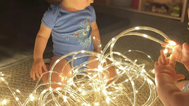Infants play with a rope light. 